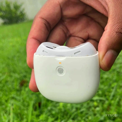FYNGE trimmer held in an open palm outdoors, front view; the small indicator light changes from green to orange and back.